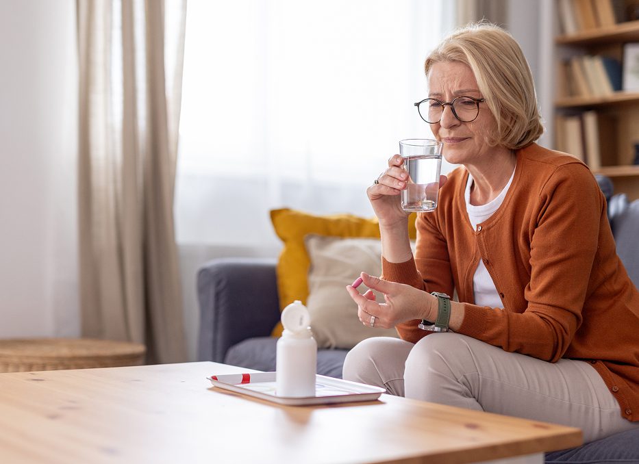 Woman taking medication with glass of water.