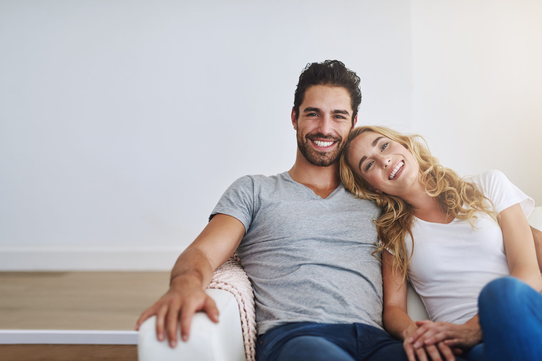 Happy couple relaxing on a couch, smiling warmly.